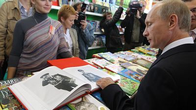 Vlagyimir Putyin könyvet nézeget a moszkvai könyvvásáron 2010. szeptember 2-án