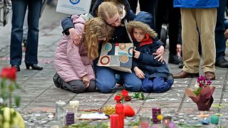 A woman and children sit and mourn for the victims of the bombings at the Place de la Bourse in the center of Brussels, Wednesday, March 23, 2016