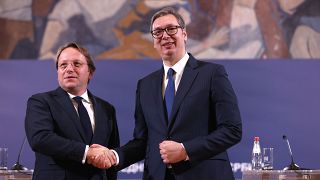 Várhelyi Olivér uniós biztos (balra) és Aleksandar Vucic szerb elnök kezet fog Belgrádban tartott sajtótájékoztatójuk végén 2022. december 2-án.