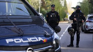 Police officers stand guard as other officers in yellow vests walk back at the cordoned off area next to the Ukrainian embassy in Madrid, Spain, Wednesday, Nov. 30, 2022. 