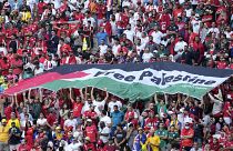 مشجعون يرفعون علمًا كتب عليه "فلسطين حرة" خلال مباراة كأس العالم بين تونس وأستراليا في الدوحة. 