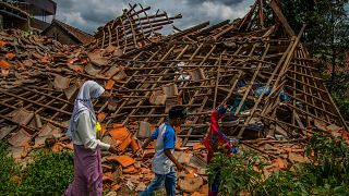 أطفال إندونيسيون يمشون وسط الركام الذي خلفه زلزال ضرب جزيرة جاوا. المكان: قرية سوجينانغ في سيانجورز بتاريخ. 1.12.22