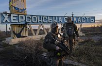 Two Ukrainian defence forces members stand next to a sign reading "Kherson region" in the outskirts of Kherson, 14 November 2022
