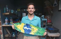 Arian Rayegani holding a skateboard manufactured in his workshop in Rio de Janeiro, Brazil