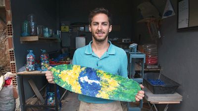 Arian Rayegani holding a skateboard manufactured in his workshop in Rio de Janeiro, Brazil