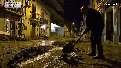 Egy szicíliai férfi lapátolja az árvíz után maradt sarat lakása elől