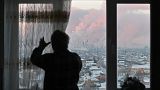 A local resident opens the curtains on a window with a view of the Gazprom Neft's oil refinery in Omsk, Russia November 18, 2022.