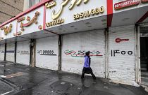 Una donna passa davanti ai negozi chiusi per sciopero in via Satarkhan, a Teheran