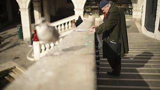 A local reads a newspaper at the Rialto bridge in Venice. Saturday, 29 February 2020.