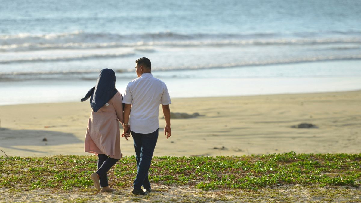FILE: A couple walks at Lhoknga beach on Valentine's Day, Aceh province on February 14, 2020.