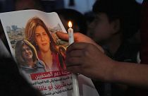 A Palestinian holds a light candle and a picture of slain Al Jazeera journalist Shireen Abu Akleh.