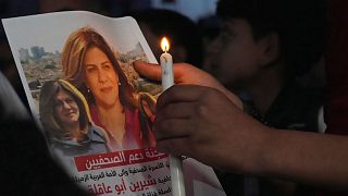 A Palestinian holds a light candle and a picture of slain Al Jazeera journalist Shireen Abu Akleh.