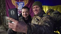 Ukrainian soldier takes a selfie with President Volodymyr Zelenskyy, left, during his visit to Sloviansk, Donetsk
