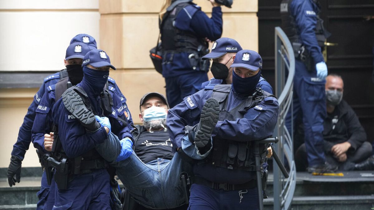 Police remove one of several protesters who had blocked the entrance of the country's constitutional court in an act of civil disobedience in Warsaw, Poland, on Aug. 30, 2022.