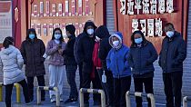 Beijing residents wearing face masks line up for their routine COVID-19 tests 