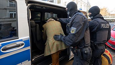 عناصر من الشرطة الملثمة يقودون مشتبهًا معتقلًا خلال مداهمة ضد "مواطنين الرايخ" في فرانكفورت، ألمانيا