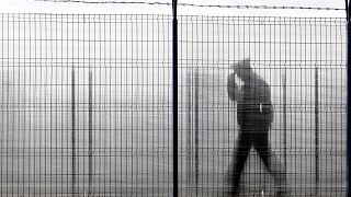 ضابط شرطة الحدود الروماني ، شوهد من خلال سياج زجاجي، يقوم بدوريات في نقطة عبور حدودية بين رومانيا ومولدوفا في رومانيا. 2011/01/10