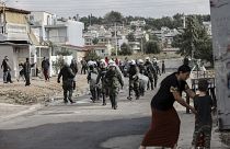Riot police walk during a raid in a Roma settlement in Aspropyrgos.