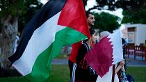 أشخاص يسيرون بالأعلام الفلسطينية والقطرية في قرية كتارا الثقافية في الدوحة. 2022/12/05
