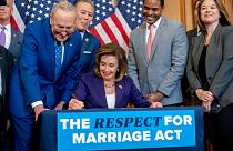 House Speaker Nancy Pelosi signs the Respect For Marriage Act with other members of Congress.
