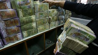 موظف يكدس أكوام من أوراق الليرة السورية في المصرف التجاري السوري بدمشق، 10 نوفمبر 2022.