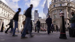 People walk outside the Bank of England, in the financial district known as The City, in London, Friday, Oct. 7, 2022.