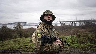 A Ukrainian serviceman patrols area near the Antonovsky Bridge which was destroyed by Russian forces after withdrawing from Kherson, Ukraine, Thursday, Dec. 8, 2022.