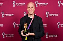 Grant Wahl smiles as he holds a World Cup replica trophy during an award ceremony in Doha, Qatar on Nov. 29, 2022.
