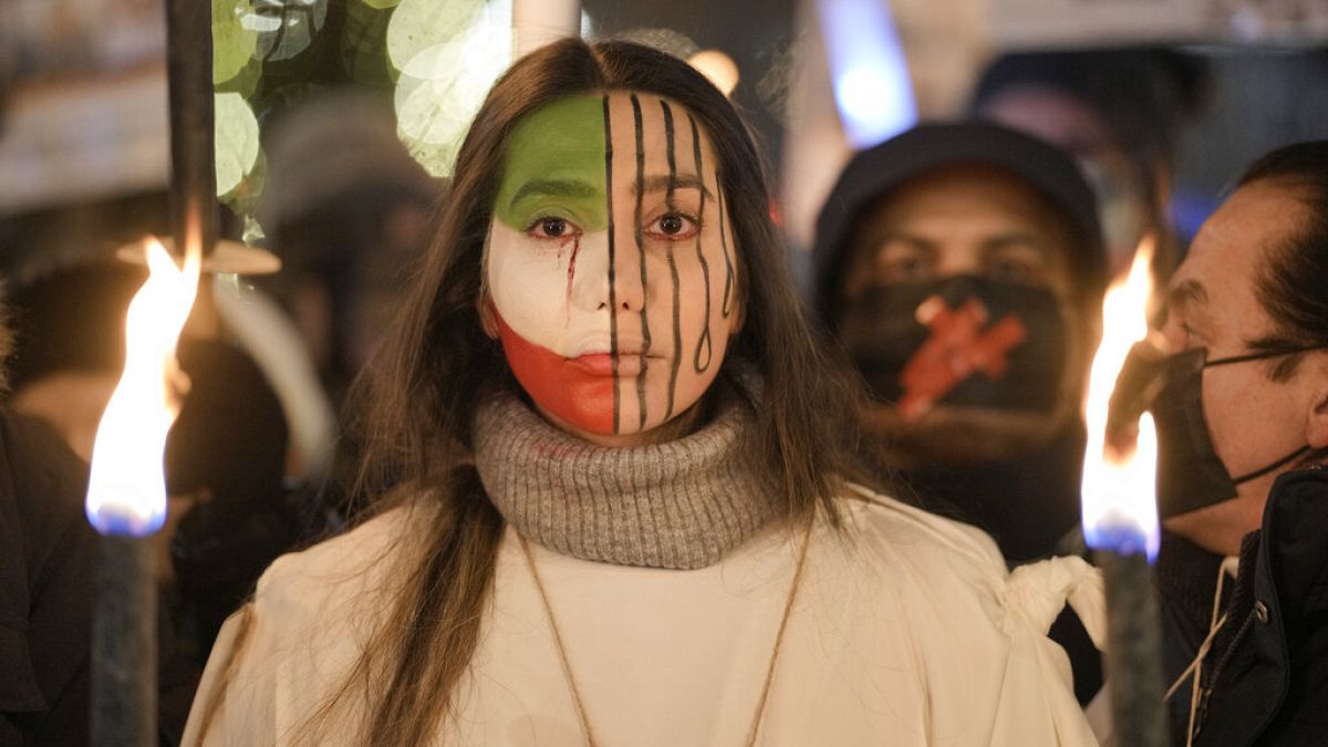 A protester with an Iranian flag painted on her face participates in a torchlight procession in honor of the Nobel Peace Prize laureates in Oslo, Norway, Saturday, Dec. 10, 20