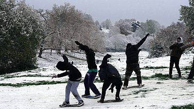 Young people slide over the snow on skateboards