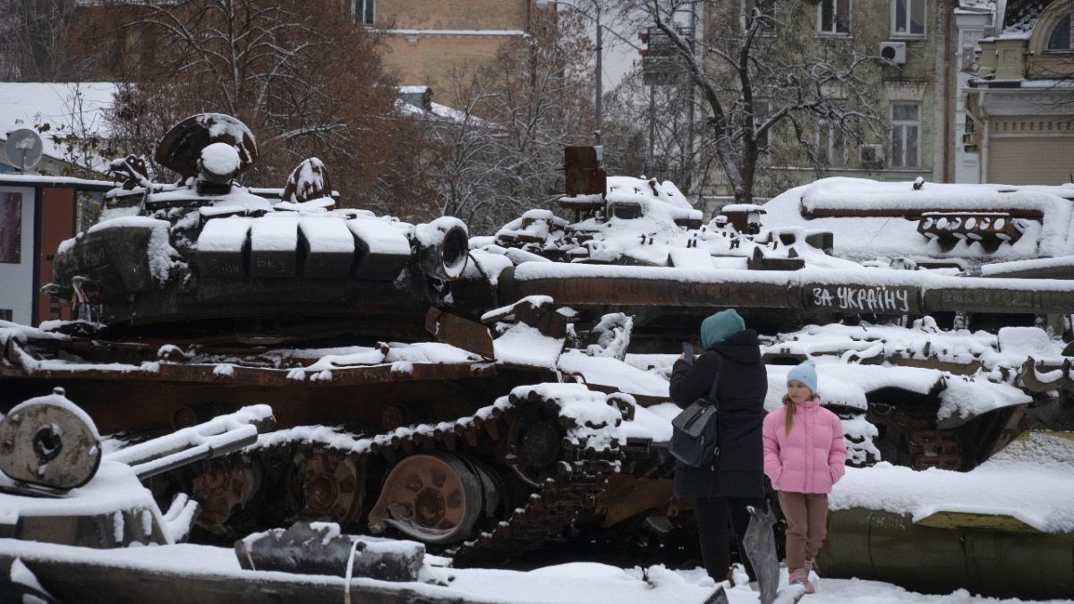 Frau und ein Kind vor beschädigten russischen Militärfahrzeugen im Zentrum von Kiew