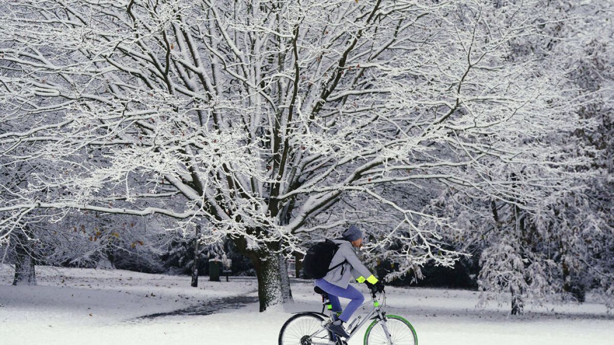 A person cycles through the snow in Greenwich Park, London on Monday