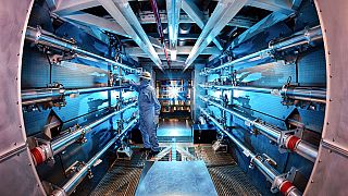 In this 2012 image provided by Lawrence Livermore National Laboratory, a technician reviews an optic inside the preamplifier support structure at the laboratory.