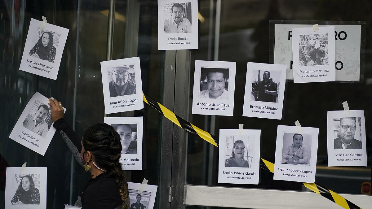 Un hombre coloca fotos de periodistas asesinados tras el asesinato del periodista Fredid Román durante una vigilia en Ciudad de México, el 24 de agosto de 2022.