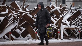 A woman passes by anti-tank hedgehogs in central Kyiv, Ukraine. 