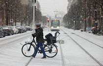 A woman pushes her bicycle across a road covered by snow in Strasbourg, eastern France.