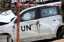 Lebanese soldiers stand behind a damaged UN peacekeeper vehicle at the scene.