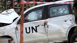 Lebanese soldiers stand behind a damaged UN peacekeeper vehicle at the scene.