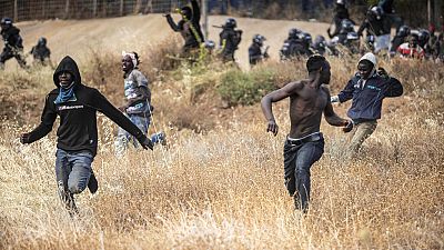 Migrants run on Spanish soil after crossing the fences separating the Spanish enclave of Melilla from Morocco in Melilla, Spain
