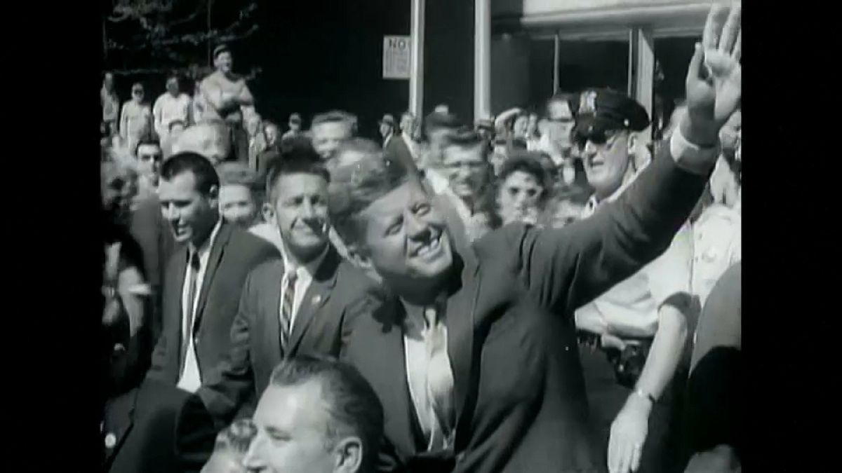 Il presidente John F. Kennedy saluta la folla dalla sua macchina. Immagine della John F. Kennedy library.