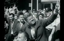 Il presidente John F. Kennedy saluta la folla dalla sua macchina. Immagine della John F. Kennedy library.