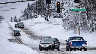 سيارات تسير ببطء عبر تقاطع في مينيسوتا الأمريكية جراء تراكم الثلوج والجليد على الطرقات بفعل العاصفة الثلجية التي اجتاحت مناطق في الولاية، 15 ديسمبر 2022.