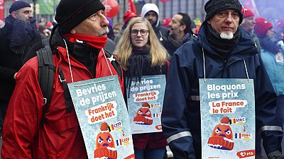 Union workers wear signs which read 'block the prices, France does it' during a demonstration in Brussels, Friday, Dec. 16, 2022.