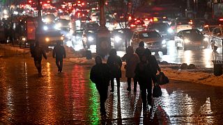 Local residents walk past cars stuck in a traffic jam as the Kyiv metro network remains out of service on December 16 2022,