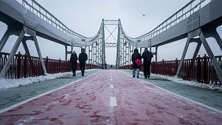 People walk on pedestrian bridge across the Dnipro river in Kyiv, Ukraine, Thursday, Dec. 15, 2022.
