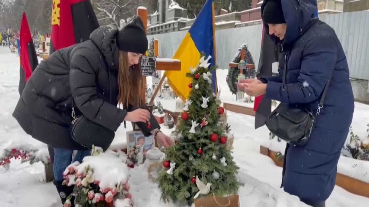 La veuve et la mère d'un soldat ukrainien tué au combat décorent un arbre de Noël sur sa tombe à Lviv,
