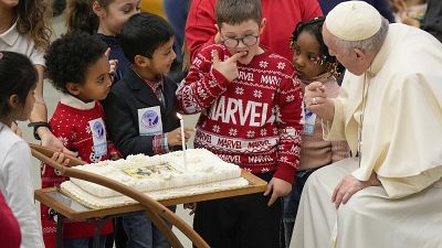 Un niño prueba la tarta de cumpleaños del papa