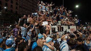 A couple kisses as other football fans celebrate Argentina's victory over France in the World Cup final, Buenos Aires, Argentina, Sunday, Dec. 18, 2022.