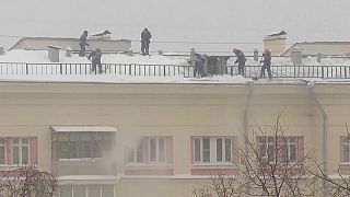 Operarios quitan la nieve de un tejado tras la enorme nevada de Moscú
