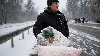 FILE: An elderly woman is coated in snow as she sits in a wheelchair after being evacuated from Irpin, on the outskirts of Kyiv, Ukraine, Tuesday, March 8, 2022.